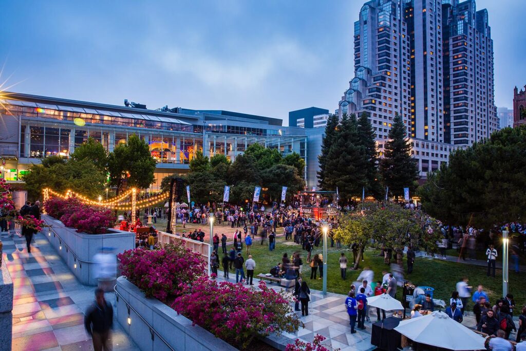 People lounging on the Yerba Buena Gardens lawn with skyscrapers in the background.