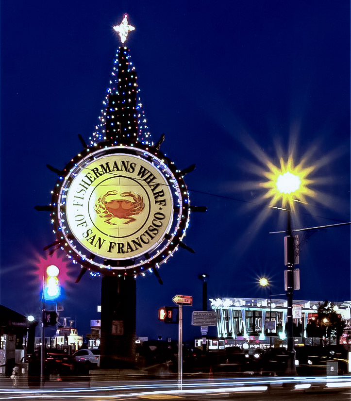 Boats lit with festive lights near Fisherman’s Wharf at night.